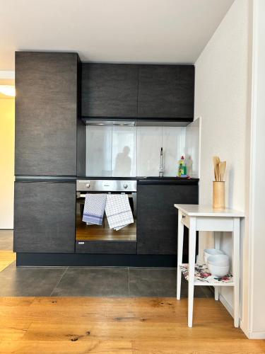 a kitchen with black cabinets and a white table at Klara 1031 - Olma, Spital, Uni St- Gallen in St. Gallen