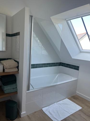 La salle de bains est pourvue d'une baignoire blanche et d'une fenêtre. dans l'établissement Port lenn, à Arzon