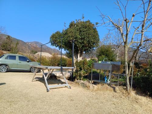 a picnic table and a car parked in a parking lot at Naganeupseong Jandi House in Suncheon