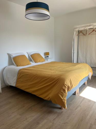 une chambre avec un grand lit avec une couverture jaune dans l'établissement Port lenn, à Arzon