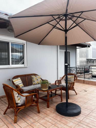 eine Terrasse mit Tisch, Stühlen und Sonnenschirm in der Unterkunft Hidden Loft in Preveza