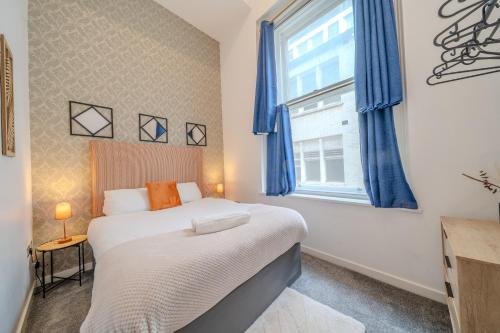 a bedroom with a bed with blue curtains and a window at Align Lux Apartments, Liverpool City Centre in Liverpool