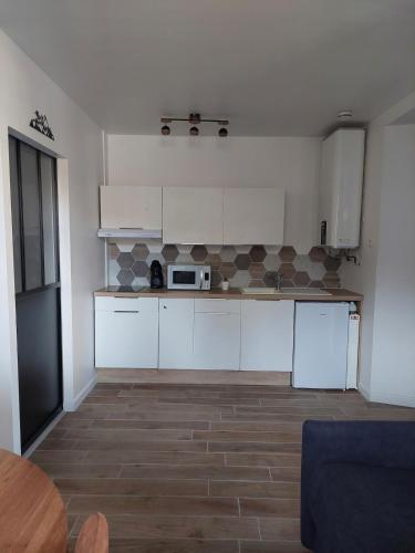 une cuisine avec des armoires blanches et un micro-ondes dans l'établissement Appartement adapté PMR 4 personnes Saint Gervais les Bains, à Saint-Gervais-les-Bains