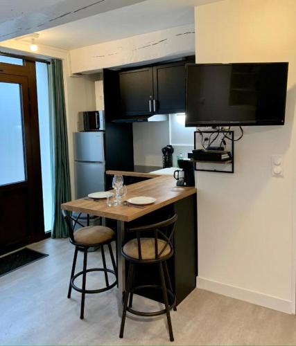 une cuisine avec une table et deux tabourets de bar dans l'établissement Confortable Studio dans le Centre historique de Rouen - 001, à Rouen