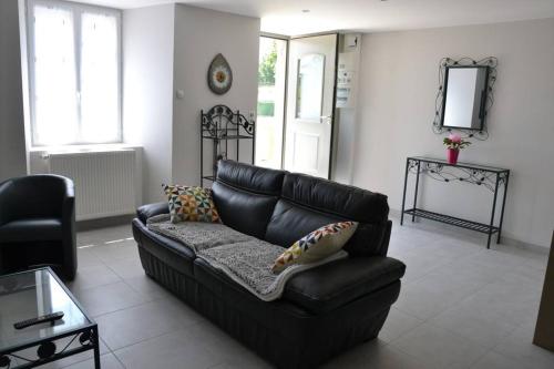 un sofá de cuero negro en una sala de estar con espejo en Gîte de Romagers, en La Chaze-de-Peyre