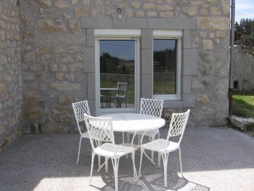 Una mesa blanca y cuatro sillas y una mesa y un edificio. en Gîte de Romagers, en La Chaze-de-Peyre