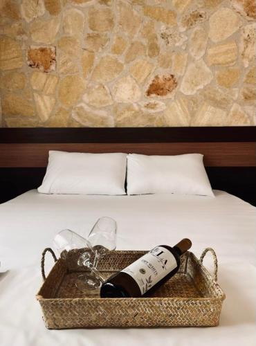 a basket with a bottle of wine and glasses on a bed at Liogerma Apartments in Pefkochori