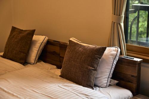 a bed with two pillows on it next to a window at Noël Kitakaruizawa Seiryu-2 Riverside retreat in Tsumagoi