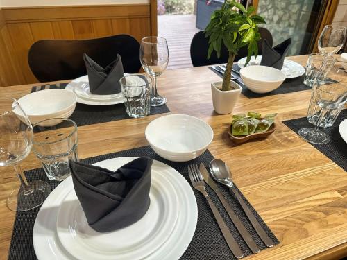 a wooden table with white plates and silverware on it at Noël Kitakaruizawa Seiryu-2 Riverside retreat in Tsumagoi