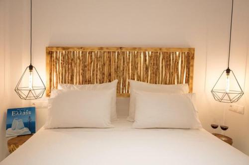 a bedroom with a bed with white pillows and two lights at Casa Centro Suites Mykonos in Mikonos