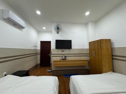 a bedroom with two beds and a desk with a tv at Khách sạn Giang Thành, khu đô thị Tây Bắc, gần bến tàu đi Phú Quốc in Rach Gia