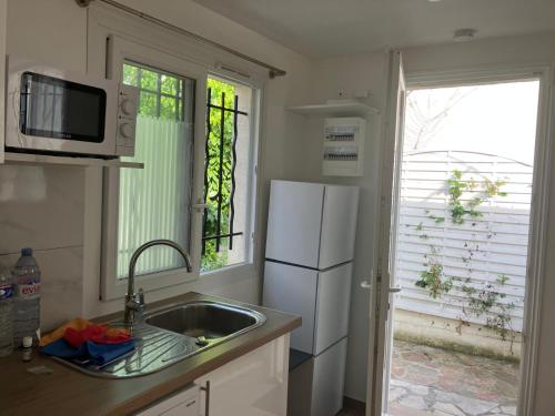une cuisine avec un évier et un réfrigérateur blanc dans l'établissement Fluo's small house, à La Courneuve