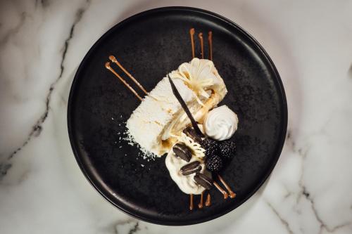 a black plate with a piece of cake and whipped cream at The Imperial Dragon Hotel in Saundersfoot