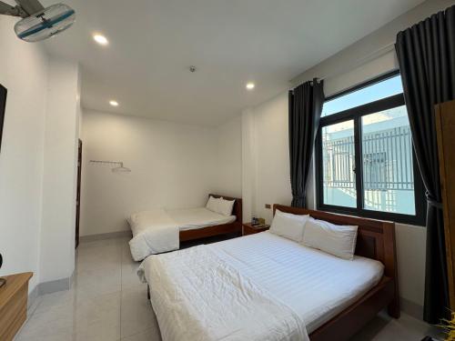 two beds in a room with a window at Khách sạn Giang Thành, khu đô thị Tây Bắc, gần bến tàu đi Phú Quốc in Rach Gia