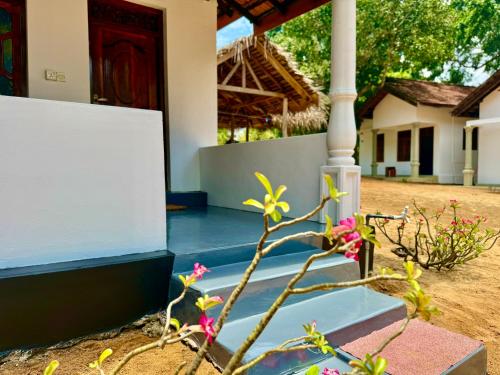 a plant with pink flowers in front of a house at Kudah Bay Surf Camp in Arugam Bay