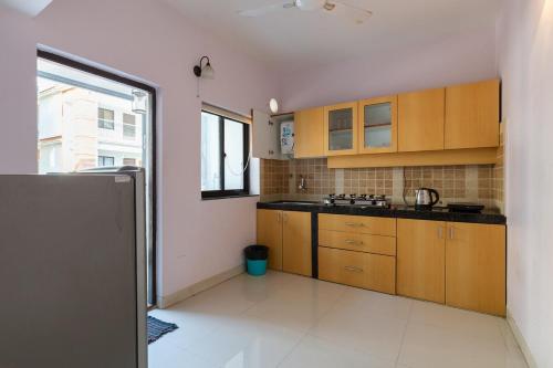 a kitchen with wooden cabinets and a large window at Luxury 2BHK Apartment with Swimming Pool near Candolim Beach in Candolim