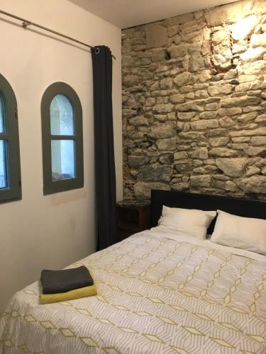 une chambre avec un lit et un mur en pierre dans l'établissement Hibiscus, à Alzonne