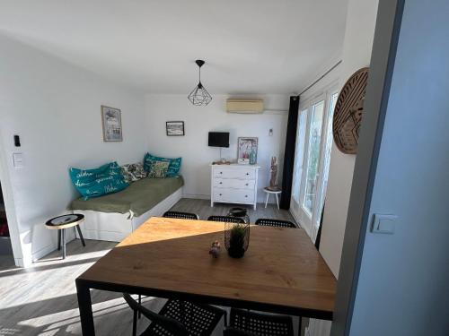 un soggiorno con un tavolo e un divano di M T2 climatisé à100m de la plage ,des bateaux ,des commerces, Une terrasse ensoleillée a Palavas-les-Flots