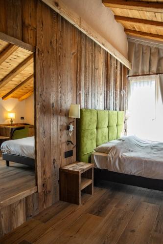 a bedroom with two beds and a green headboard at Hotel La Montanina in Livigno
