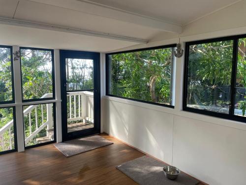 an empty room with large windows and wooden floors at Pet friendly beachfront home- sleeps 8 in Toogoom
