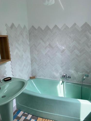 une salle de bain avec une baignoire verte et un lavabo dans l'établissement Le Bocage, maison avec grand jardin et parking, à Étretat
