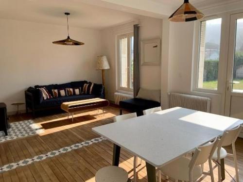 un salon avec une table blanche et un canapé dans l'établissement Le Bocage, maison avec grand jardin et parking, à Étretat