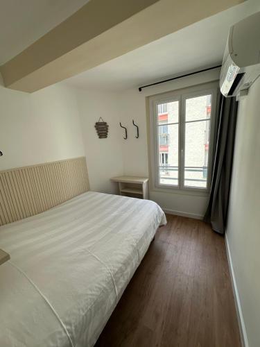 ein Schlafzimmer mit einem weißen Bett und einem Fenster in der Unterkunft Charming and very central 2 rooms apartment in Bandol