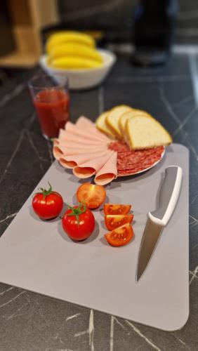 a cutting board with tomatoes and bread and a knife at Mobile homes Eva in Biograd na Moru