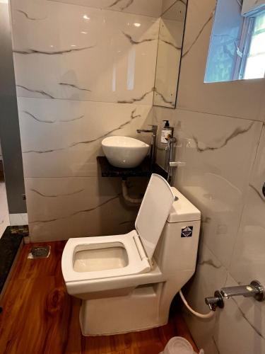 a bathroom with a white toilet and a sink at Aaditya Inn Rooms & Banquet hall in Hinjewadi