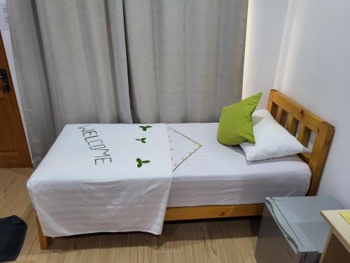 a small bed in a small room with green pillows at Leaf fish guesthouse Maldives in Keyodhoo