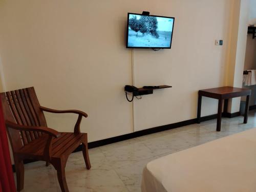 a room with a chair and a television on a wall at Diora Hotel in Ratnapura