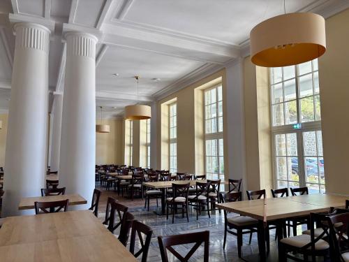 a dining room with tables and chairs and windows at Dom Zdrojowy CECHINI in Żegiestów