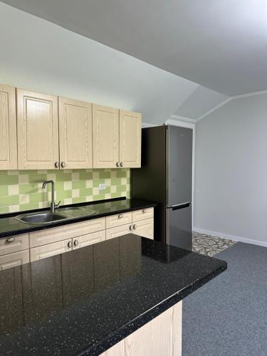 a kitchen with a black counter top and a refrigerator at A quiet area in Durleşti