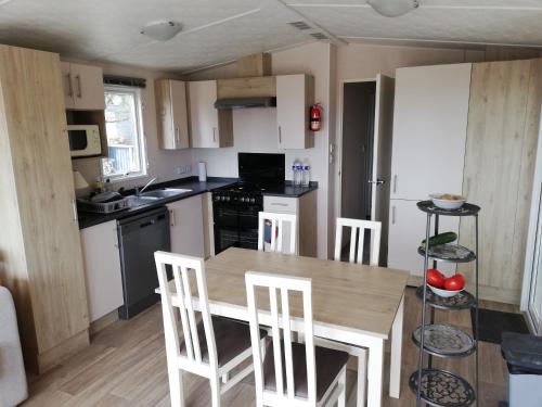une petite cuisine avec une table et des chaises en bois dans l'établissement Mobile Home - Vue Baie de Bonne Anse - La Palmyre - 2ch, clim, 6 pers, aux Mathes