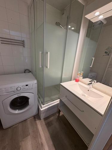 une salle de bain avec une machine à laver et un lavabo dans l'établissement Bel appartement en bord de mer, à Lacanau