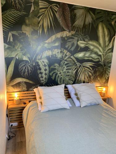 - une chambre avec un lit orné d'une fresque murale représentant des plantes dans l'établissement Bel appartement en bord de mer, à Lacanau