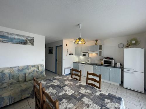 une cuisine avec une table et un réfrigérateur blanc dans l'établissement T2 cabine 6 pers, terrasse, parking, animaux acceptés - FR-1-379-141, à Vieux-Boucau-les-Bains