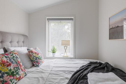 a white bedroom with a bed and a window at Charming seaside guesthouse in Väddö
