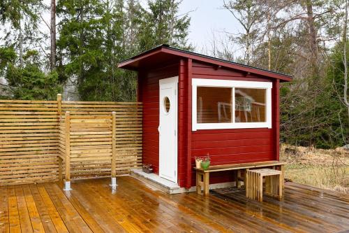 a red shed with a bench on a wooden deck at Charming seaside guesthouse in Väddö
