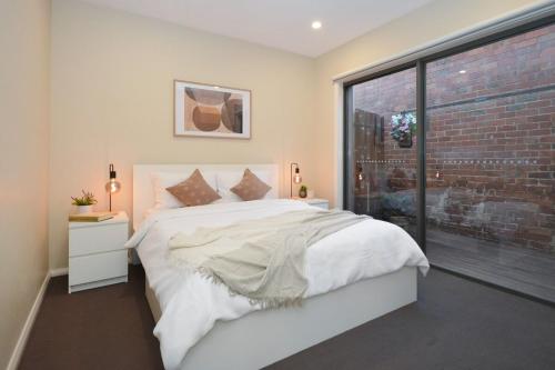 Un dormitorio con una cama blanca y una pared de ladrillo. en Luxury Townhouse Stay, en Melbourne
