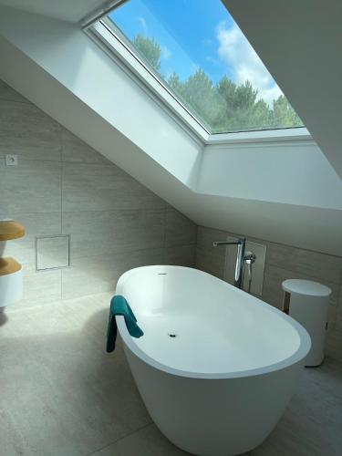 une baignoire blanche dans une salle de bain avec un puits de lumière dans l'établissement Villa Californie avec piscine près du circuit des 24H, à Changé