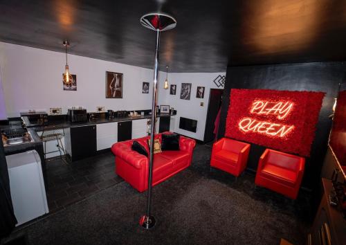 a living room with a red couch and a neon sign at Play Queen - A Playful Unique Hot Tub Retreat in Sedgley