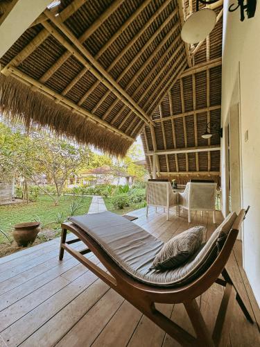 a hammock on a deck in a house at Vayam Boutique Resort Gili Asahan in Gili Asahan