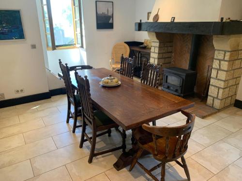 a dining room with a wooden table and a fireplace at Beautiful Big Home with Swimming Pool and Nature Grounds in Auterrive
