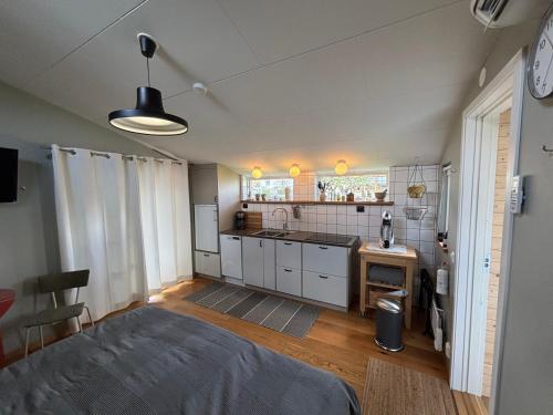 a small kitchen with white cabinets and a bed in a room at Eget boende i privat uthuslänga in Alingsås