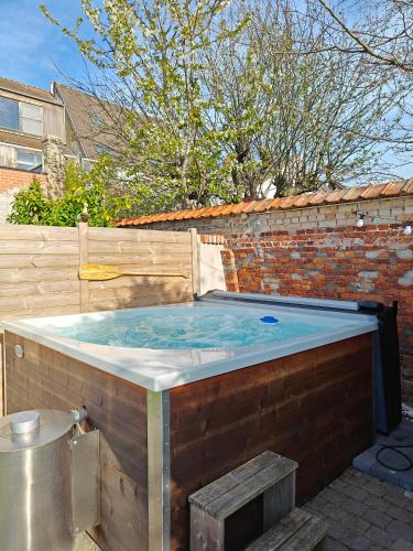 a hot tub in a backyard with a brick wall at Gastenverblijf De Arend in Nieuwpoort