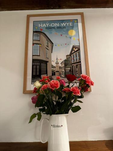a vase with flowers on a table with a picture at Hay On Wye Welsh Townhouse in Hay centre in Hay-on-Wye
