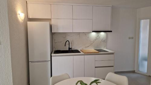 a white kitchen with a sink and a refrigerator at Apartment Dubravka in Podgora