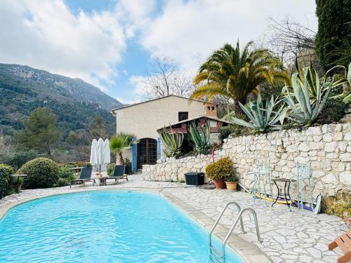 - une piscine en face d'un mur en pierre dans l'établissement Villa au charme incroyable et piscine, à Saint-Jeannet