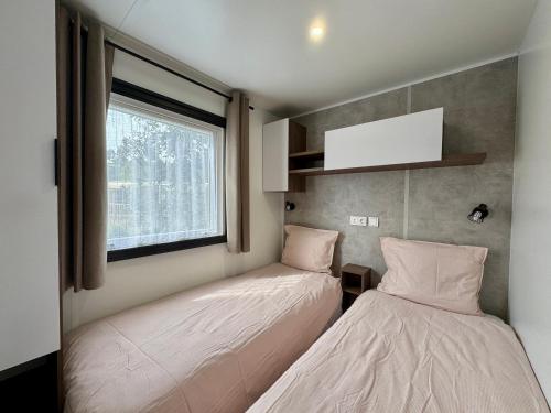 zwei Betten in einem kleinen Zimmer mit Fenster in der Unterkunft Un toit sur le bassin Bungalow solaire in Lège-Cap-Ferret